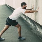 95365311 – strong man stretching calf and leaning on wall